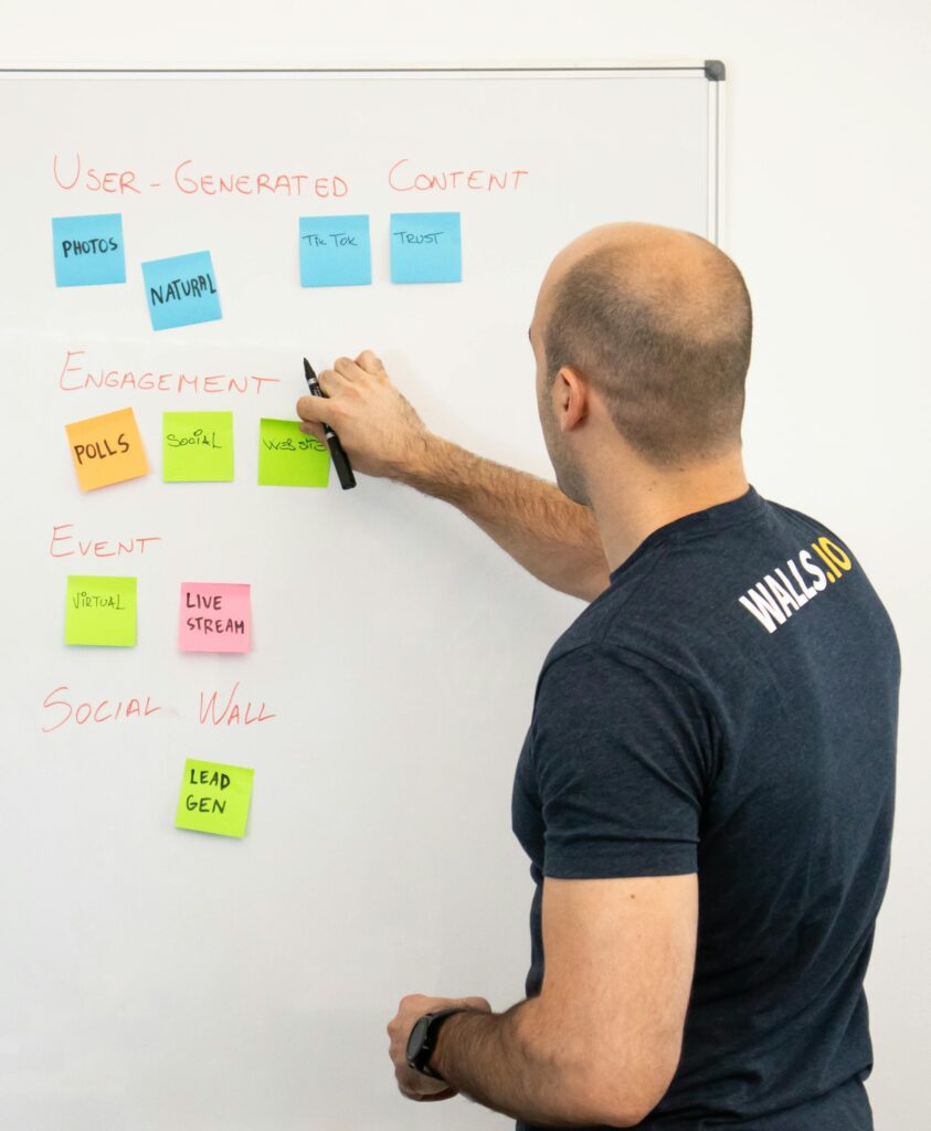 pexels-photo-17714158-17714158 Man analyzing marketing content strategies using sticky notes on a whiteboard.
